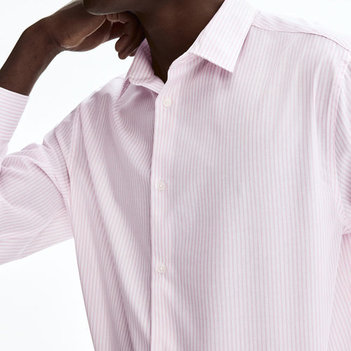 A close-up of a man wearing a light pink and white vertically striped button-down dress shirt, shown from the chest up against a plain white background.