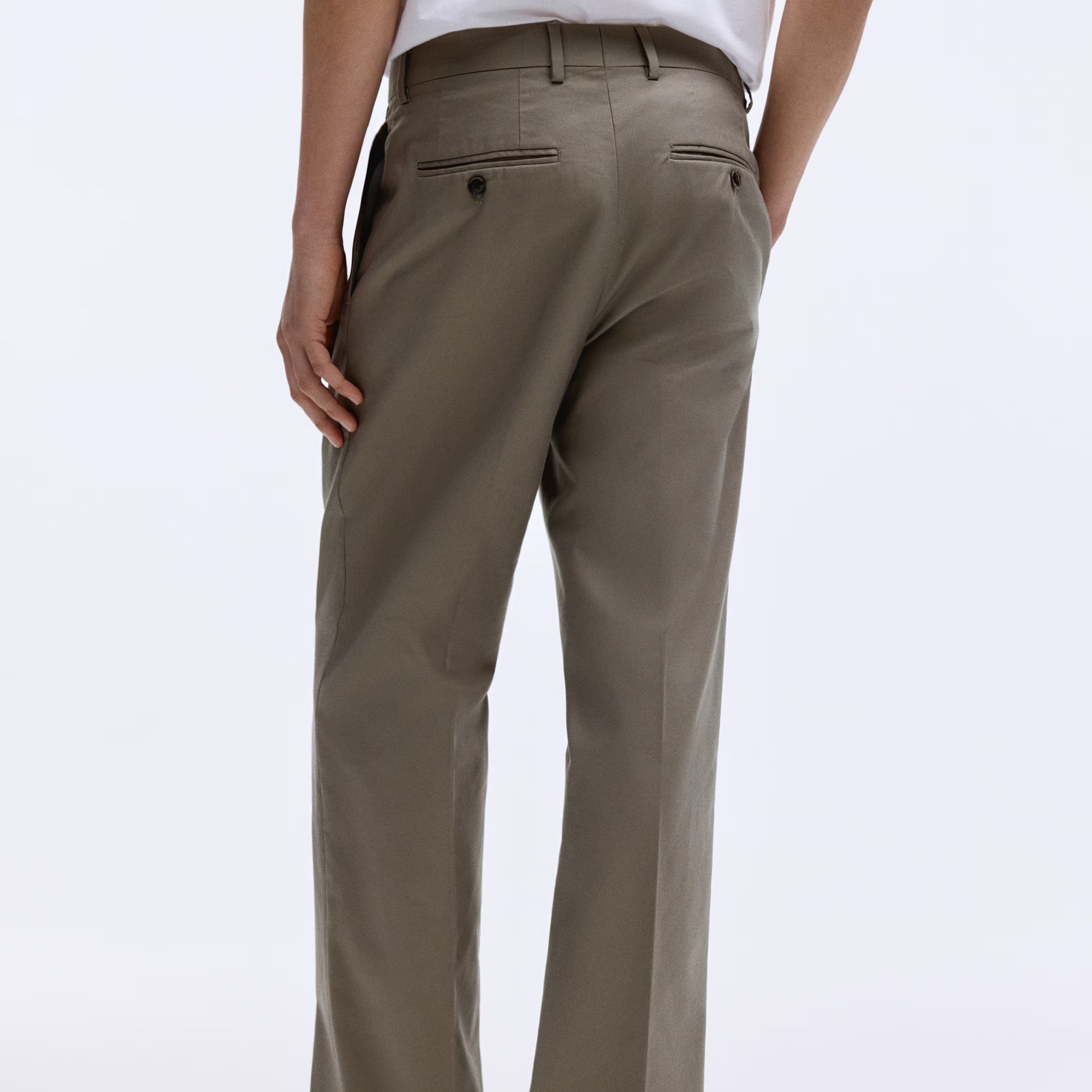 A person shown from the back wearing straight-leg khaki trousers and a white t-shirt, standing against a plain white studio background.