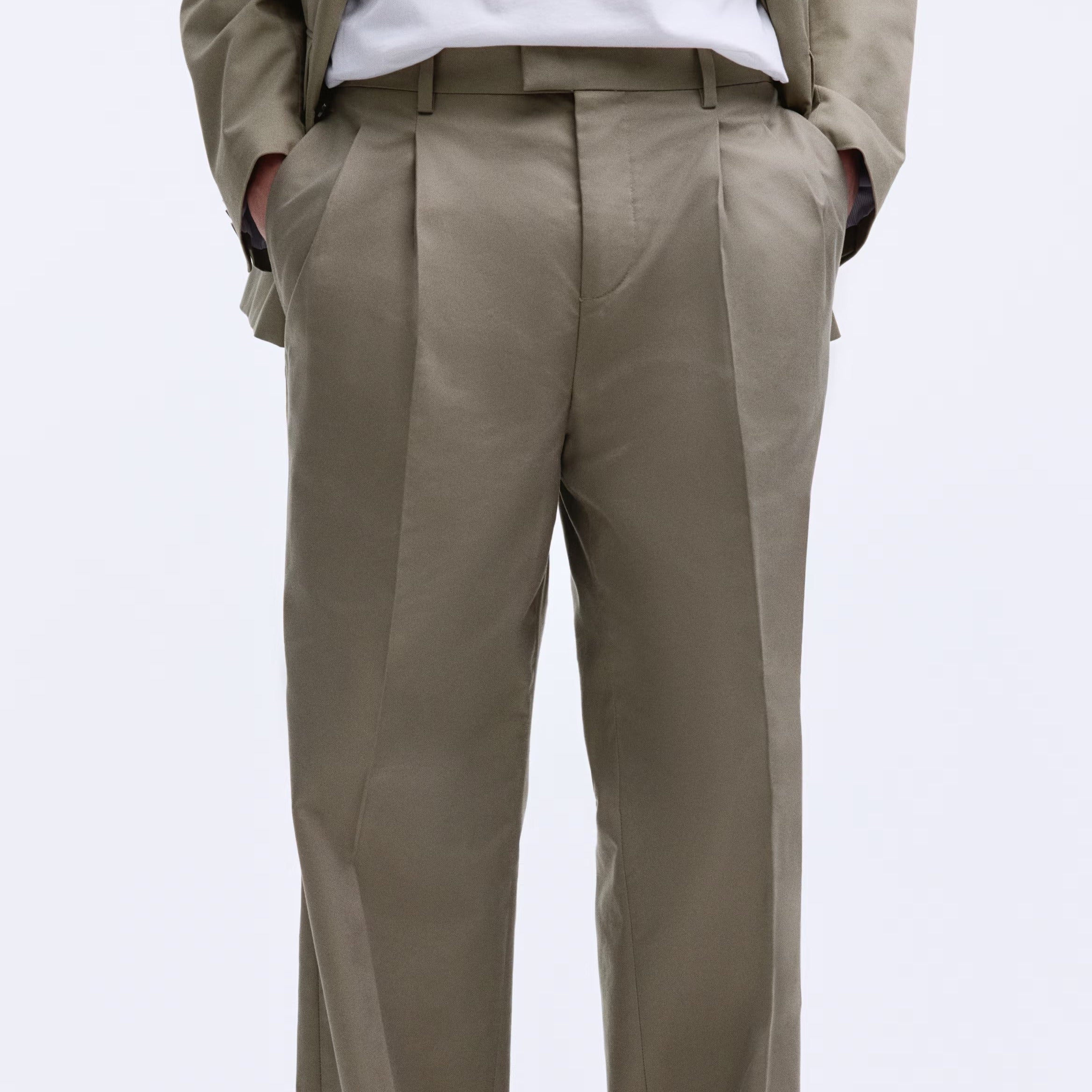Beige pants worn by a person on a white background